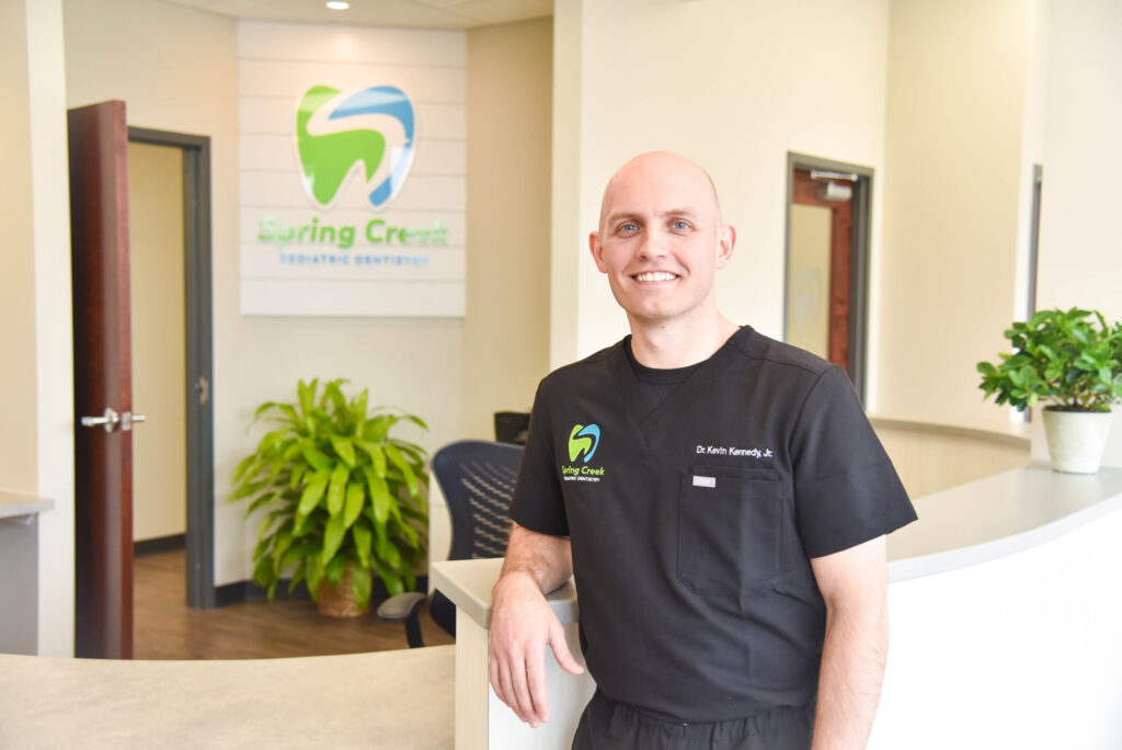 A photo of Dr. Kennedy in front of the reception desk at Spring Creek Pediatric Dentistry.
