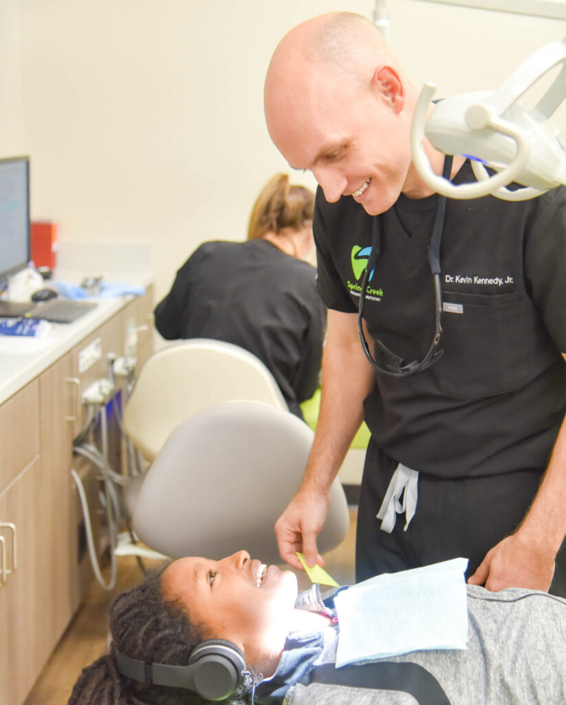 pediatric sedation dentistry. A young woman is being treated at Spring Creek Pediatric Dentistry by Dr. Kennedy - both are smiling in the photo.